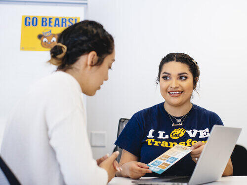 Transfer student sharing a flyer with another student